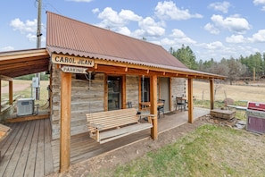A wooden cabin with a porch, a bench, and a sign that reads 'CAROL JEAN PARKING.'