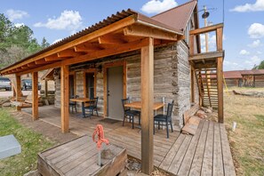 Un chalet rustique doté d’une terrasse en bois, de meubles d’extérieur et d’une façade en pierre.