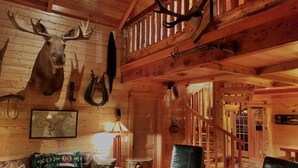 A cozy cabin interior with a wooden ceiling, a mounted moose head, a leather sofa, and a wooden chair. -  Spring /Summer availability!  On 2 creeks, wood burning fireplc, log gazebo. (Rhododendron)