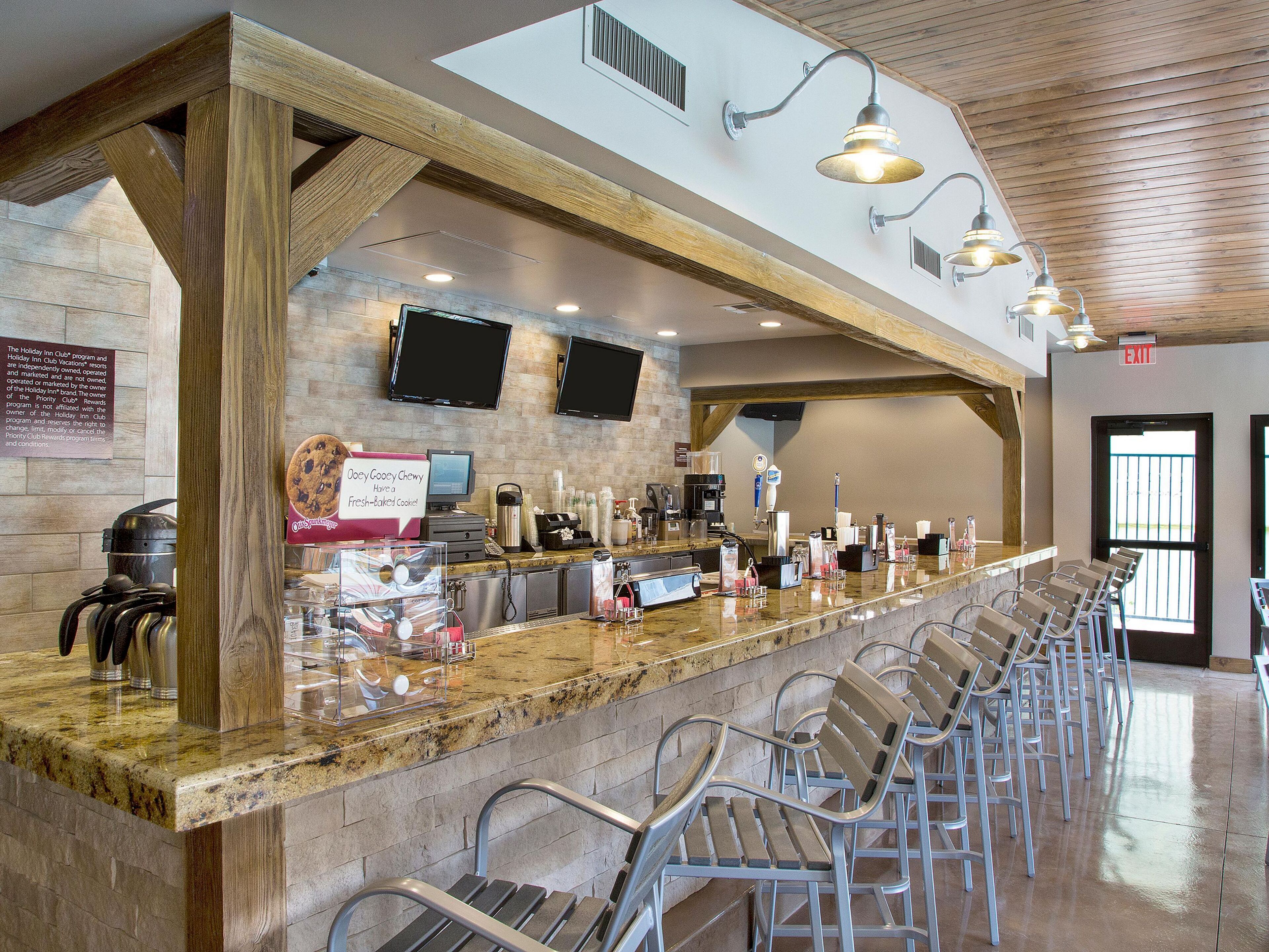 A bar area with a long counter, multiple seating options, and a stone wall backdrop.