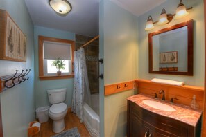 Een bad/douchecombinatie, een haardroger, handdoeken, toiletpapier