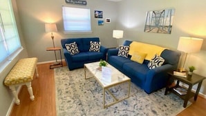 A living room with a blue sofa set, a coffee table, a patterned rug, and a bench.