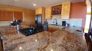 A kitchen with granite countertops, wooden cabinets, a gas stove, a refrigerator, and a coffee maker. - Book now for hunting and ski seasons. Huge mountain views! (Pagosa Springs)