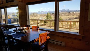 A wooden dining table with chairs, large windows with a view of mountains, and a wooden deck. - Book now for hunting and ski seasons. Huge mountain views! (Pagosa Springs)