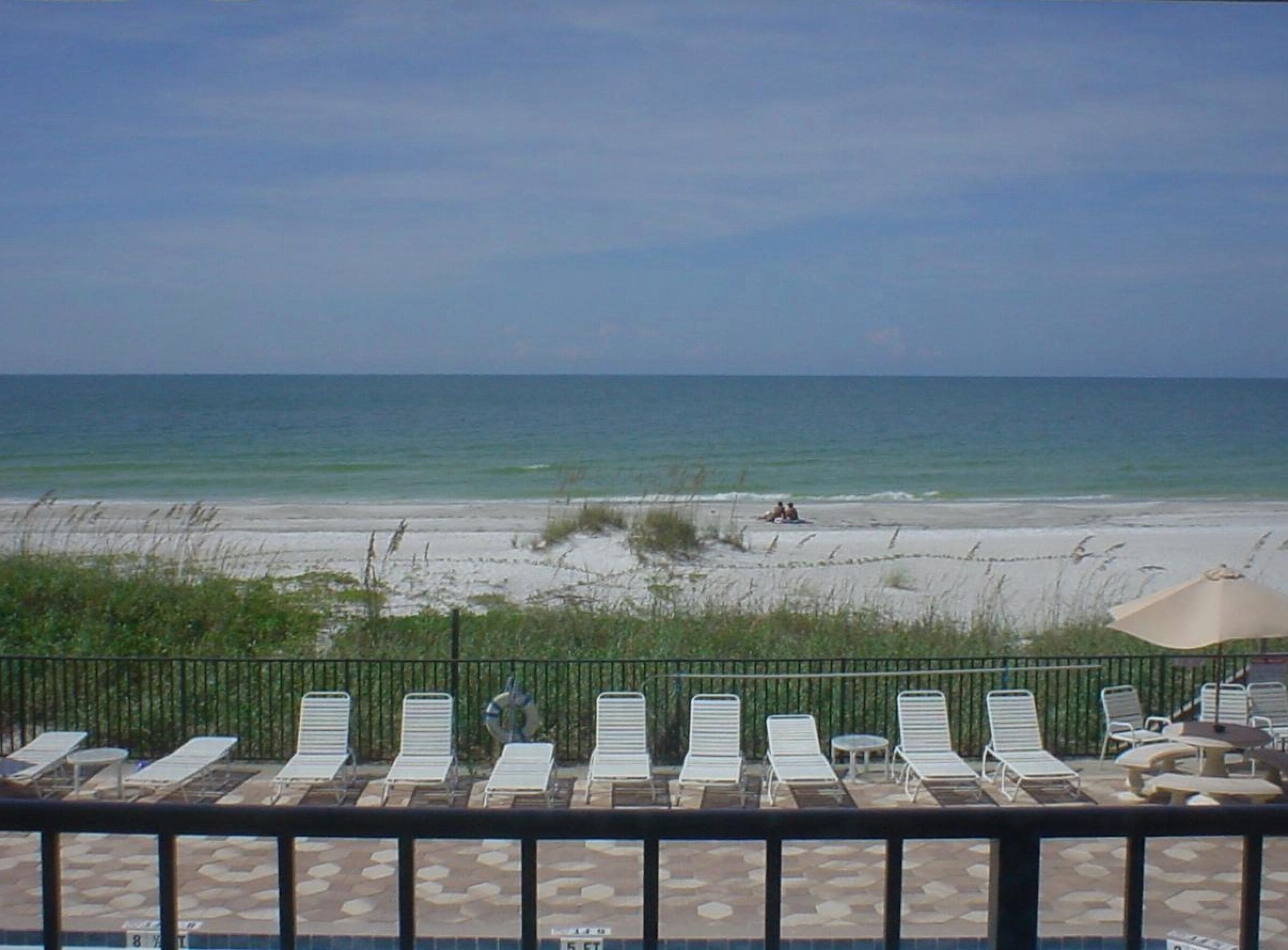 Blick auf einen Strand mit Liegestühlen und Poolbereich.