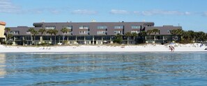 Un hotel sulla spiaggia con diversi piani, balconi e una spiaggia sabbiosa sullo sfondo.