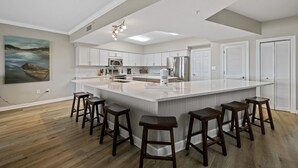 Una cocina moderna con una isla grande, armarios blancos y taburetes de madera.