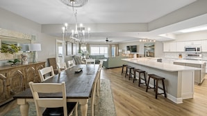 Una cocina amplia con una isla grande, mesa de comedor de madera y taburetes de bar.