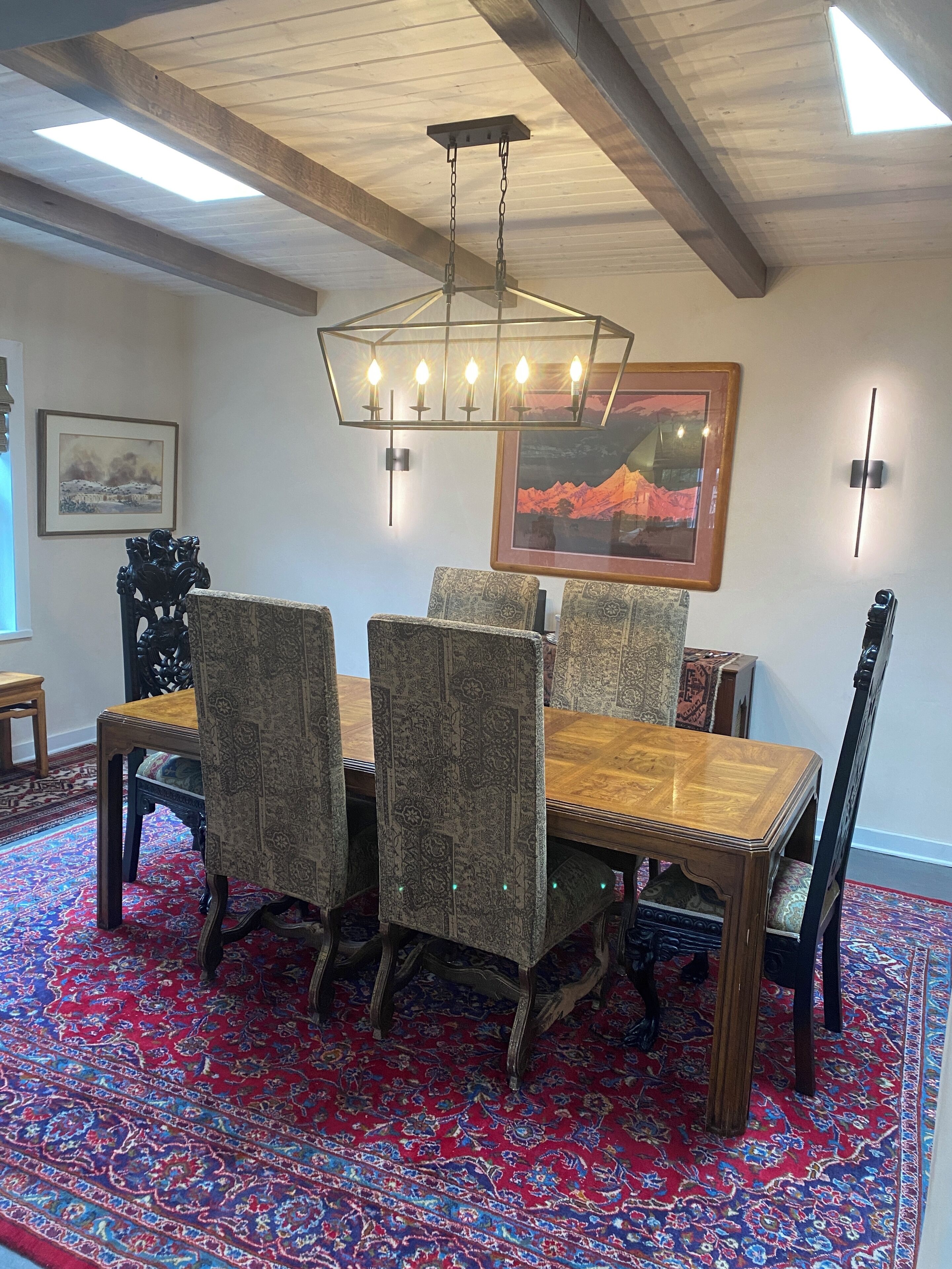 Un coin repas avec une table et des chaises en bois, un tapis à motifs et un lustre.