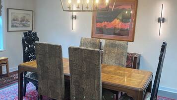 Un coin repas avec une table et des chaises en bois, un tapis à motifs et un lustre.