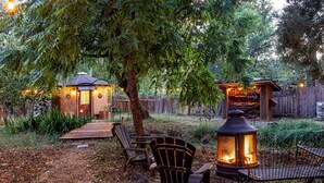 Un jardin avec une terrasse en bois, un espace salon extérieur et un foyer.