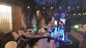 An outdoor dining area with tables set for a formal event, surrounded by chairs with white and purple covers, and string lights overhead. - La Casa de Don Pedro, Beautiful house in Antigua Guatemala (Antigua Guatemala)