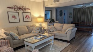 Una sala de estar con dos sofás color beige, una mesa de centro y cojines a rayas.