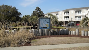 Señal de 'Stardboard by the Sea' con vista a un edificio y una zona ajardinada con césped y árboles.