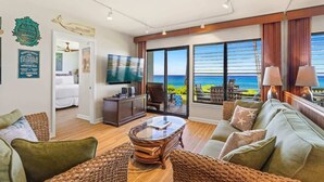 Amplia sala de estar con un gran ventanal que ofrece vista al océano, una zona de estar confortable con una mesa de centro y un televisor en la pared.