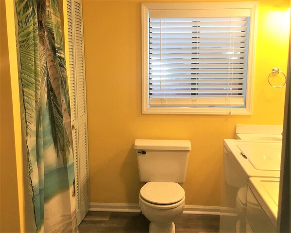 A bathroom with a toilet, a window with blinds, and a sink. - Waterfront, Large deck, Pet friendly, Golf cart. (Myrtle Beach)