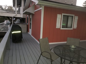 A covered outdoor deck with a barbecue grill, a table with chairs, and a window with shutters. - Waterfront, Large deck, Pet friendly, Golf cart. (Myrtle Beach)