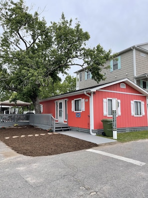 A red single-story house with a front porch, a mailbox, and a street sign. - Waterfront, Large deck, Pet friendly, Golf cart. (Myrtle Beach)