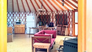 Un intérieur spacieux avec un plafond haut, des poutres en bois, un canapé rouge, une table en bois et un barbecue.