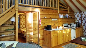 Un chalet en bois accueillant, doté d’une chambre en mezzanine, d’une cuisine équipée du strict nécessaire et d’un escalier menant à l’espace nuit situé à l’étage.