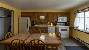 A compact kitchen with wooden cabinets, a refrigerator, a microwave, a stove, and a sink.