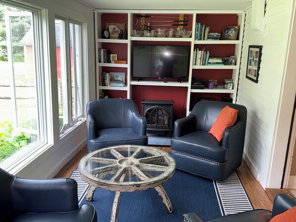 A cozy living room with two leather armchairs, a glass coffee table, and a bookshelf filled with books and decorative items.