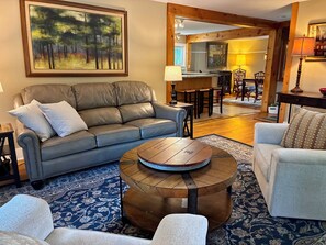 A living room with a leather sofa, a round coffee table, a patterned rug, and a painting on the wall.