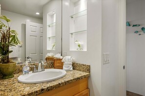 A bathroom with a granite countertop, white sink, and a potted plant. - Unobstructed Oceanfront Views! Kahana Reef 422 (Lahaina)