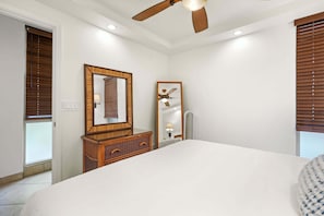 Ein Schlafzimmer mit Bett, einem Holzschrank, Deckenventilator und Spiegel.