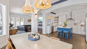 A spacious kitchen with white cabinets, a central island with stools, and pendant lighting.