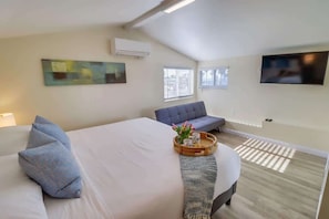 Habitación de hotel con cama, sofá, televisión y obras de arte en las paredes.