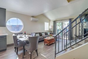 Uma sala de estar moderna com área de jantar, escada e vista para o exterior.