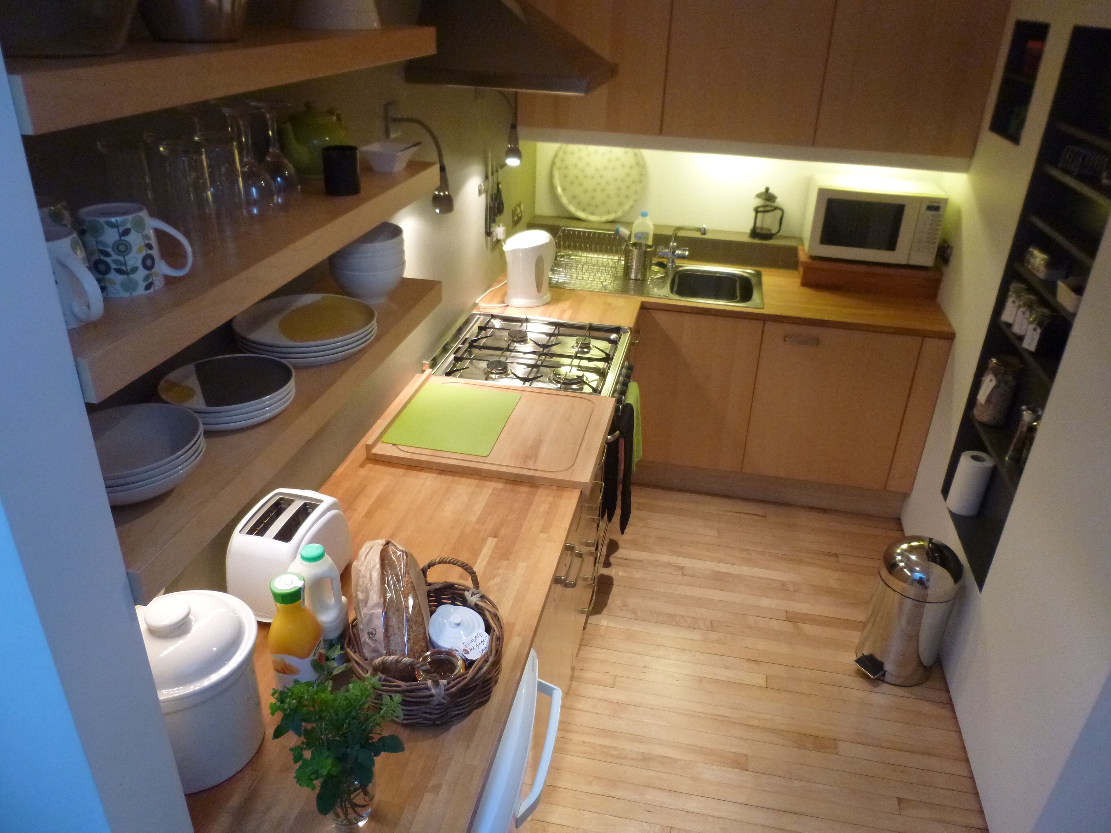 A compact kitchen with wooden countertops, a gas stove, a microwave, and various kitchen utensils.