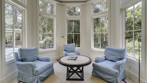 A room with a bay window, two blue armchairs, a round table, and a floor lamp. - 6 Piping Plover-A true smart home with media room! 146 Yard walk to the Beach (Hilton Head Island)