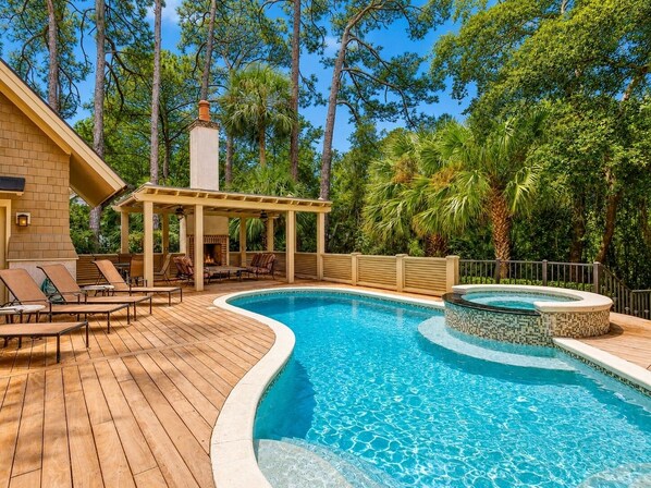 Un espace piscine avec des chaises longues, un coin salon abrité et un jacuzzi.