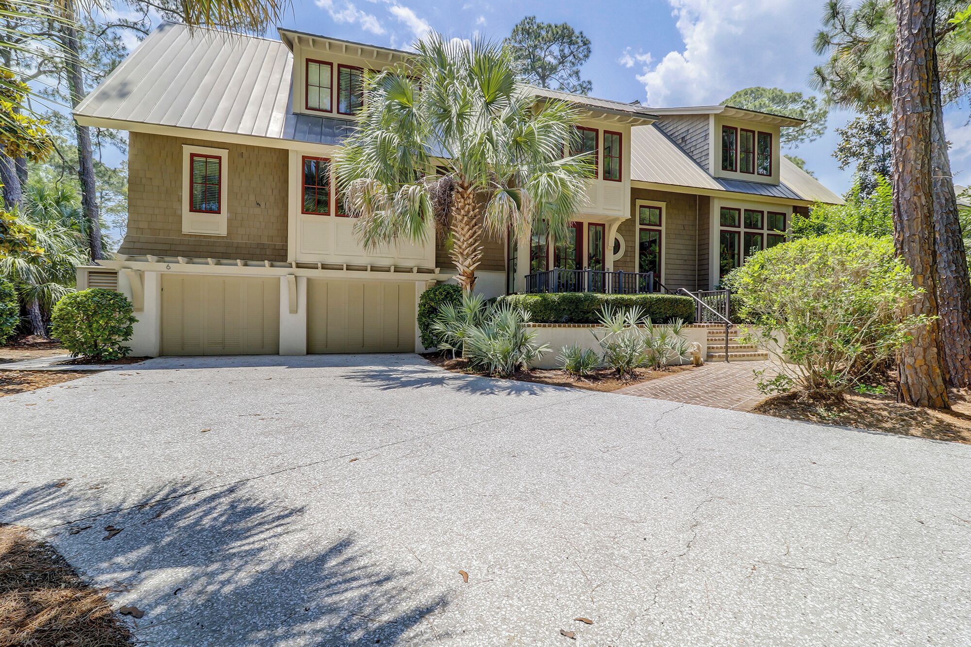 A two-story house with a garage, surrounded by landscaped gardens and trees.
