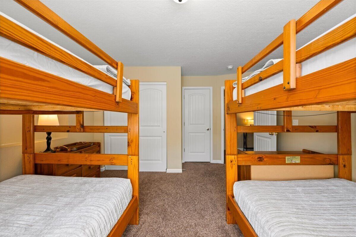 Une chambre avec deux lits superposés, une commode et une lampe.