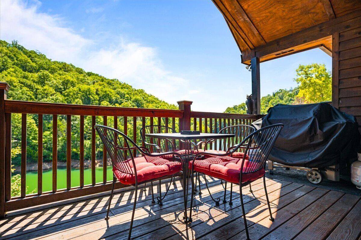 Une terrasse en bois avec une table et des chaises, donnant sur un paysage verdoyant.