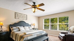 A bedroom with a bed, bedside tables, a ceiling fan, a window with blinds, and a chair. - Beautiful Lakefront Getaway - Sleeps 26 - Norris Lake’s Best Location (La Follette)