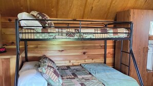 A bunk bed with a patterned bedspread, a wooden ceiling, and a chair with a woven seat. - Vacation Cabin On 5 Acres With Pond . Sleeps 3 (kalispell)