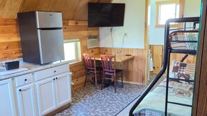 A rustic cabin with a kitchenette, a dining area, and a bunk bed. - Vacation Cabin On 5 Acres With Pond . Sleeps 3 (kalispell)