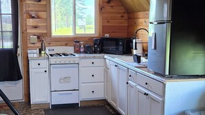 A cozy cabin with a kitchen, a dining area, and a living space. - Vacation Cabin On 5 Acres With Pond . Sleeps 3 (kalispell)