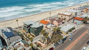 Zona residencial costera con casas, una playa y una carretera con coches.