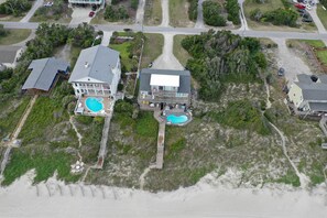 An aerial view of a coastal property with a large house featuring a swimming pool, a dock, and a beach access path. - Affordable Oceanfront w/ Private Pool! (Emerald Isle)