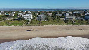Une zone résidentielle côtière avec des maisons situées près de la plage, un rivage sablonneux et des vagues qui se brisent sur le rivage.