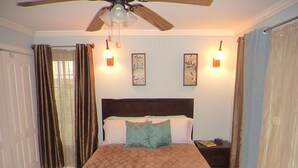 Ein Schlafzimmer mit Bett, Nachttisch, Deckenventilator und zwei Wandleuchten.