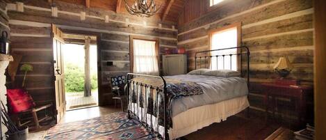 Un dormitorio tipo cabaña con estructura de cama de metal, alfombra estampada y candelabro.