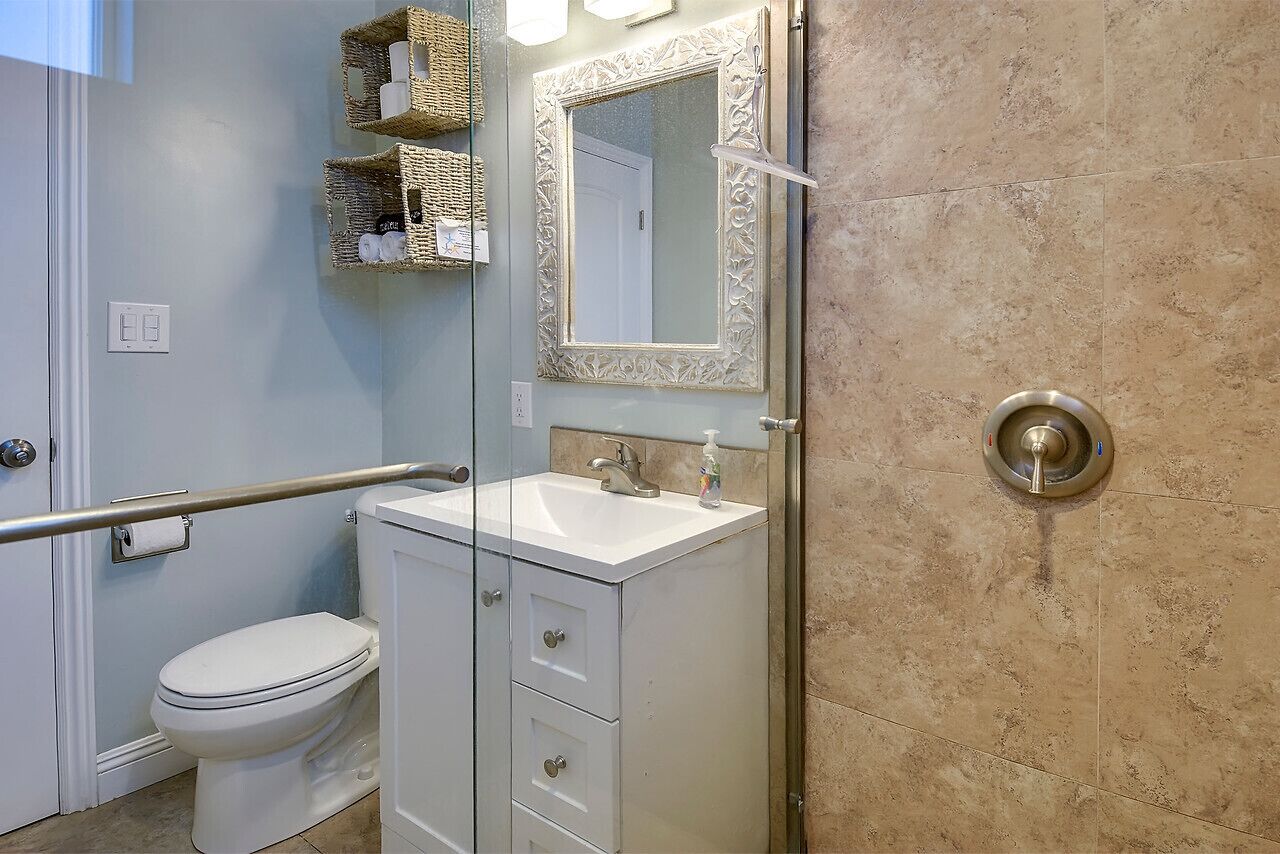 A bathroom with a white toilet, a sink with a mirror, and a shower area.