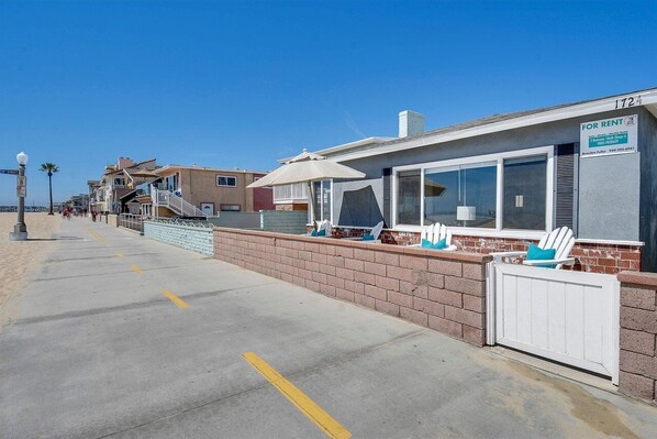 A beachfront property with a rental sign, a covered patio, and a view of the beach.