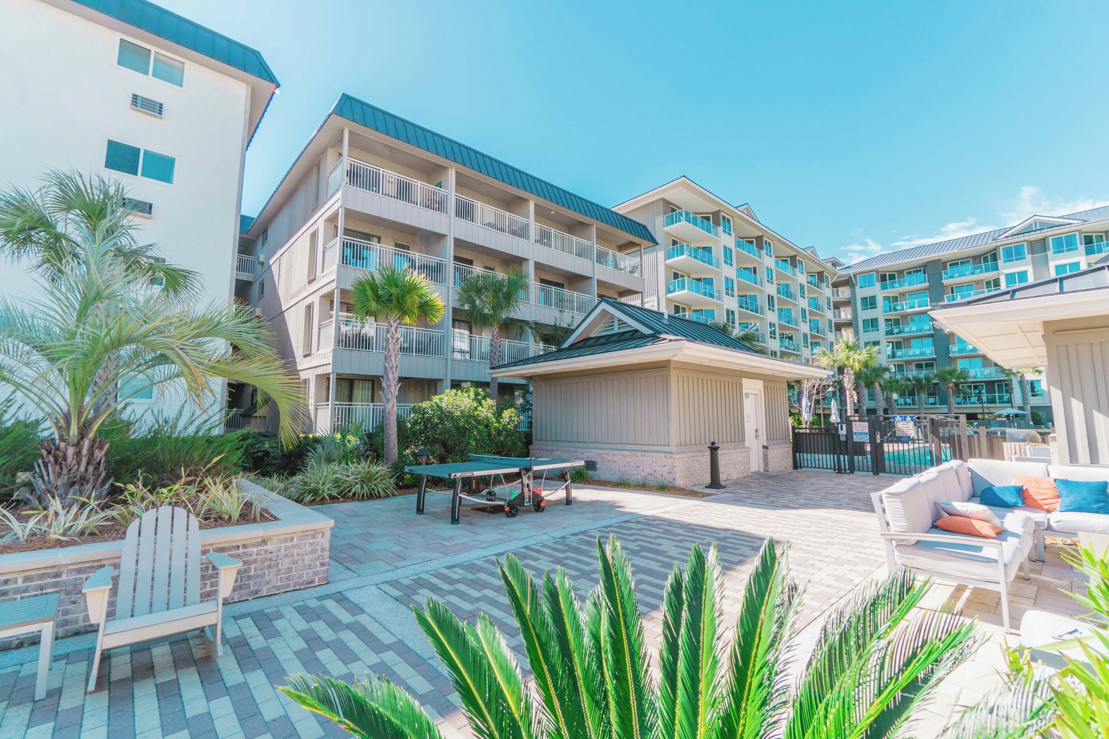 A hotel courtyard with outdoor seating, a ping pong table, and a pool area.